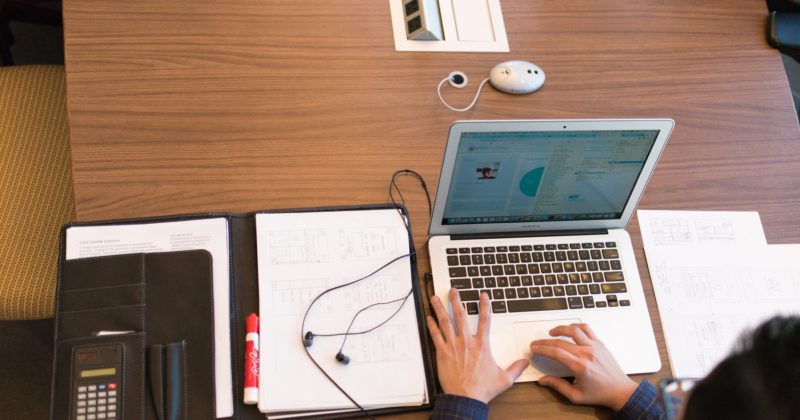 A man diligently working on a laptop at a conference table while avoiding LinkedIn profile mistakes.