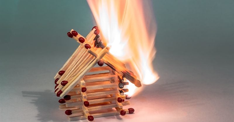 A burning match house set against a gray background.