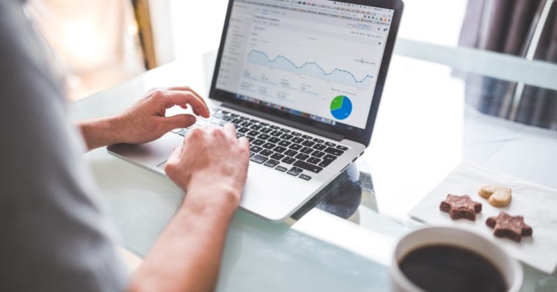 A man using a laptop to analyze a graph.