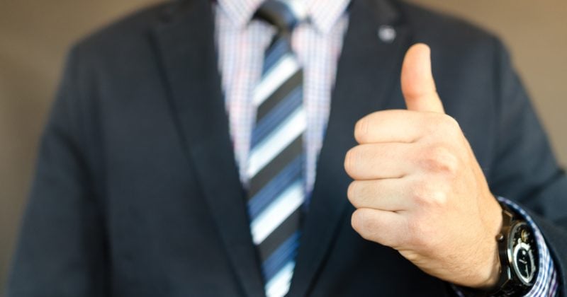 A man in a suit is giving a thumbs up to highlight the importance of having a good website for Google's "Long Click".