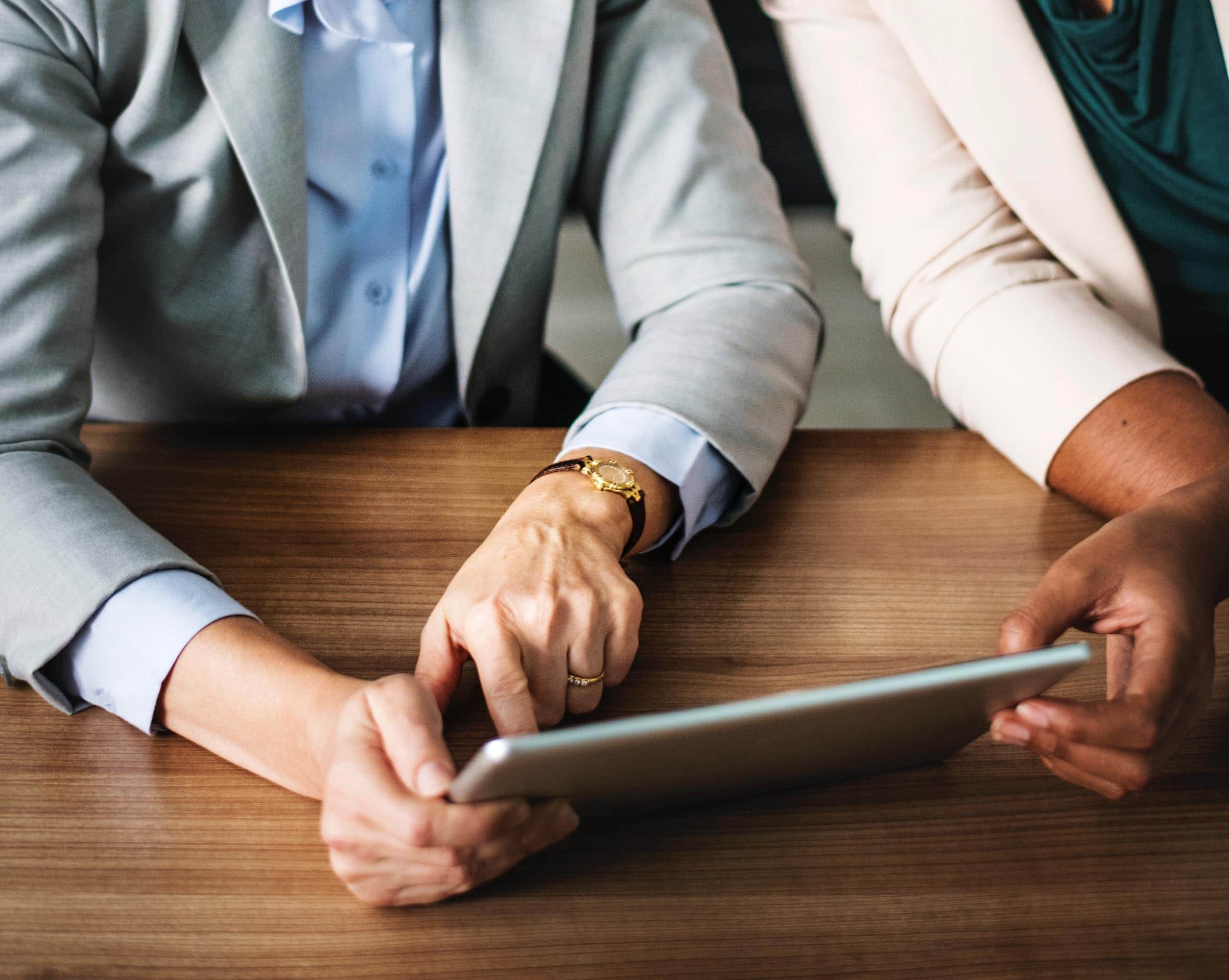 Two professionals in a meeting utilizing a tablet for ebooks.