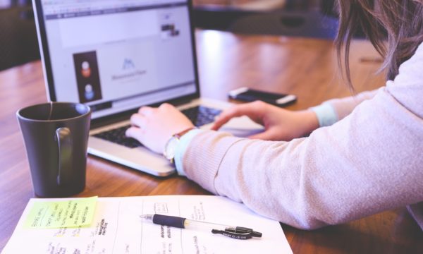 A woman optimizes content marketing strategies on a laptop at a wooden table.