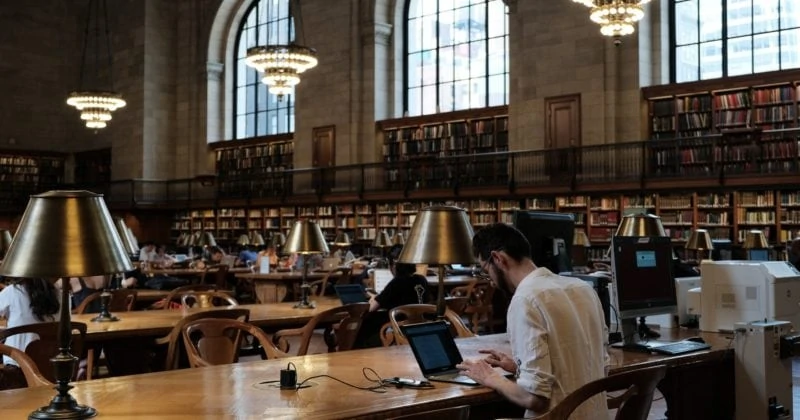 A group of people sitting at tables in Elmhurst Public Library, making education accessible to all.