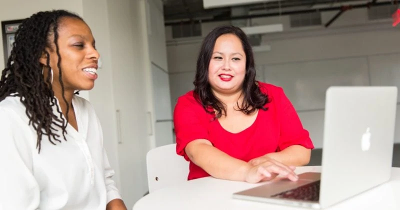 Two women sitting at a table creating opportunity with a laptop.