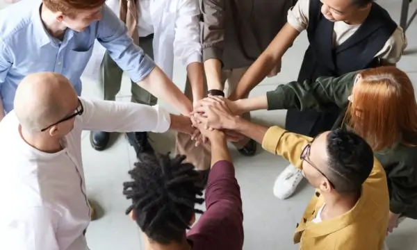 A group of colleagues holding hands in an office, discussing how to sell their WordPress business.