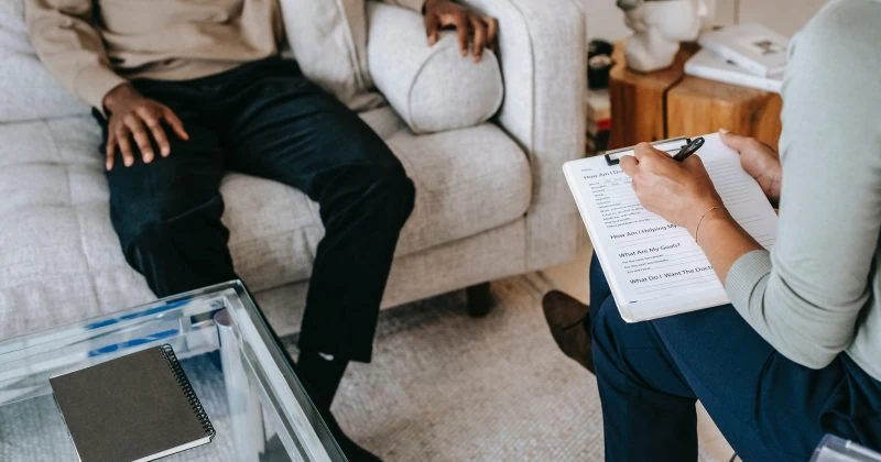 A man joins a woman on a couch, discussing their best practicing sites.