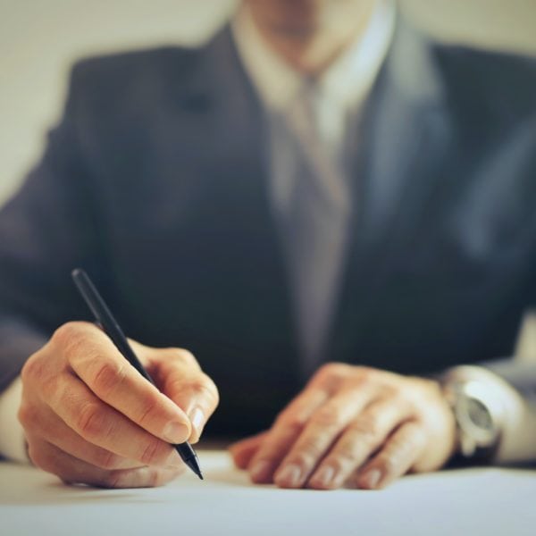 A law firm attorney signing a document with a pen.