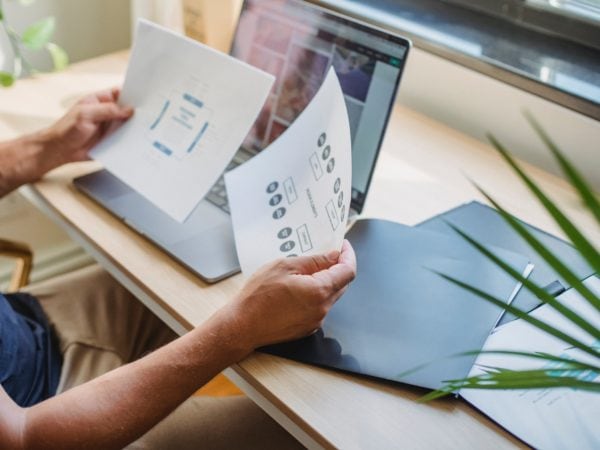 A recruiter is working on a laptop with papers in front of him.