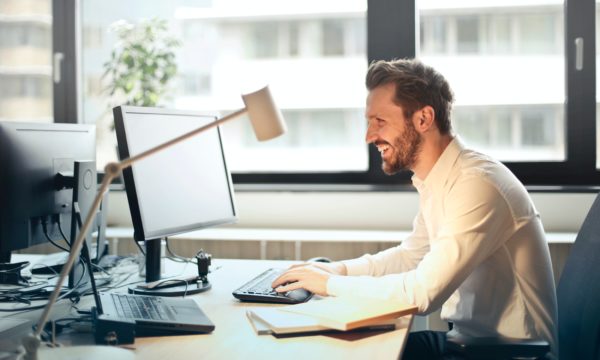 A therapist providing online counseling, sitting at a desk working on a computer.
