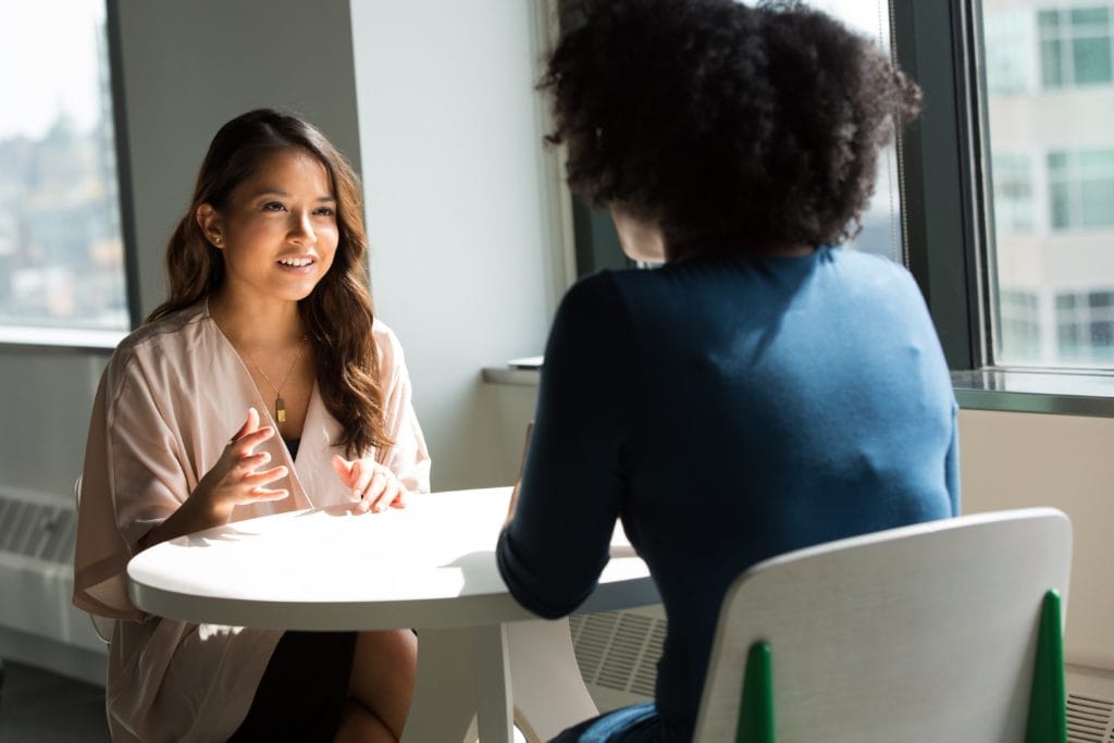 Two women discussing interior design at a table in an office.