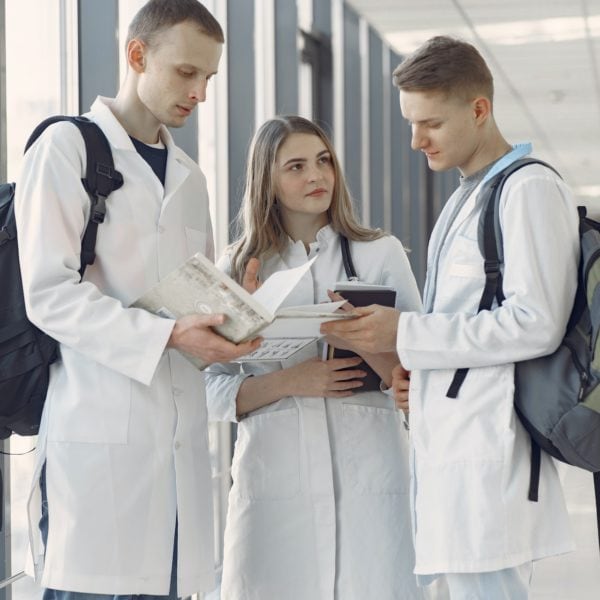 Three medical professionals in lab coats standing in a hallway.