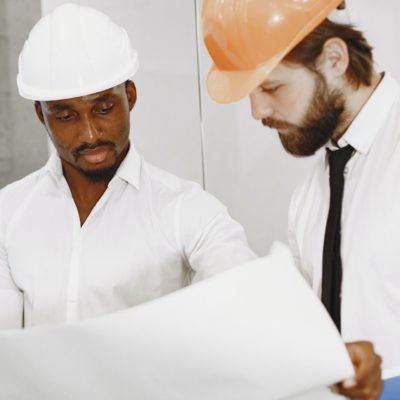 Two construction workers in hard hats examining blueprints.