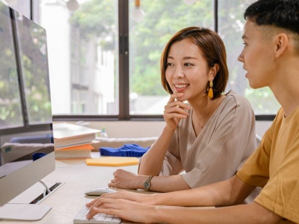 Two recruiters sitting in front of a computer screening potential candidates.