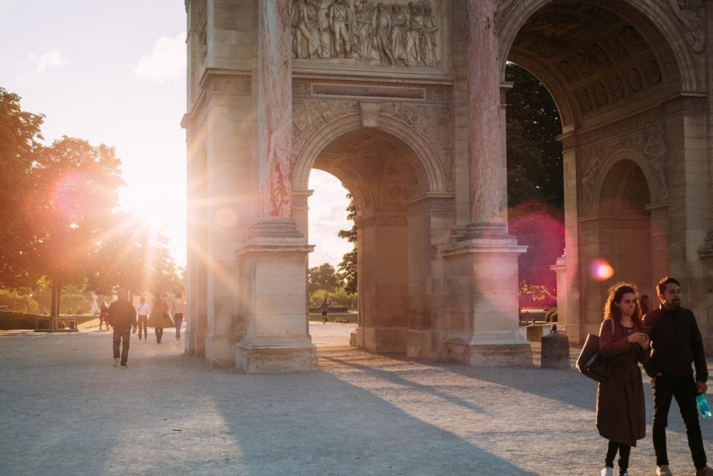 Two tourists standing in front of the iconic arc de triomphe.