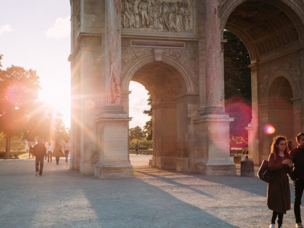 Two tourists standing in front of the iconic arc de triomphe.