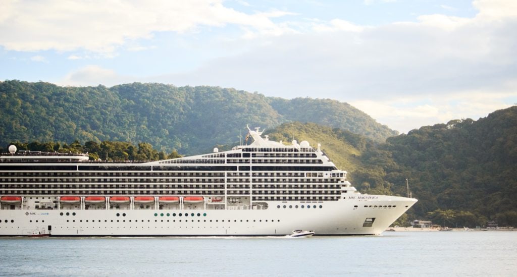 A spacious cruise ship docked in a picturesque body of water, offering extraordinary travel and tourism experiences.