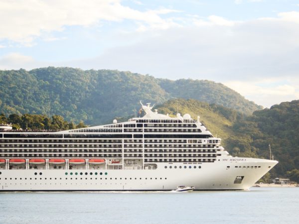 A spacious cruise ship docked in a picturesque body of water, offering extraordinary travel and tourism experiences.