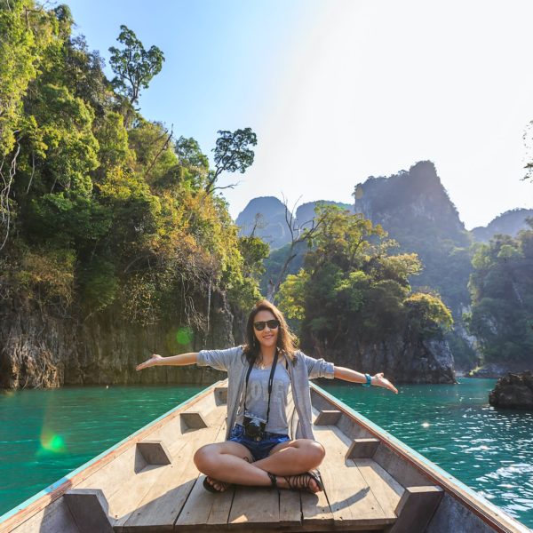 A woman enjoying travel on a boat with her arms outstretched.