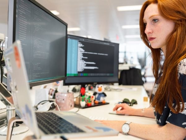 A recruiter working on a laptop in front of two monitors.