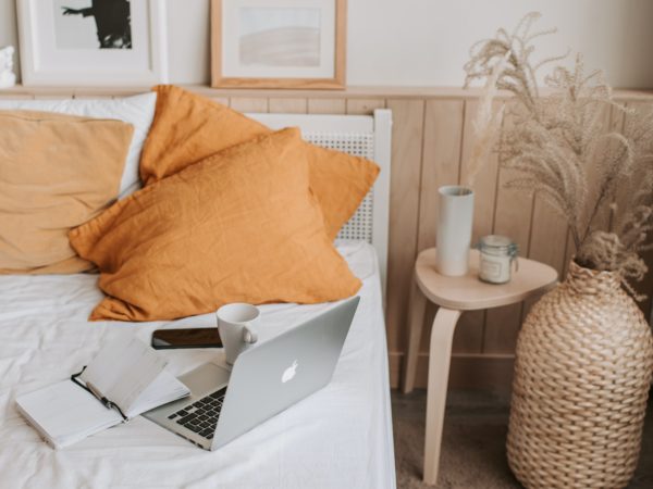 An architecturally-inspired bed adorned with a laptop and flip flops.