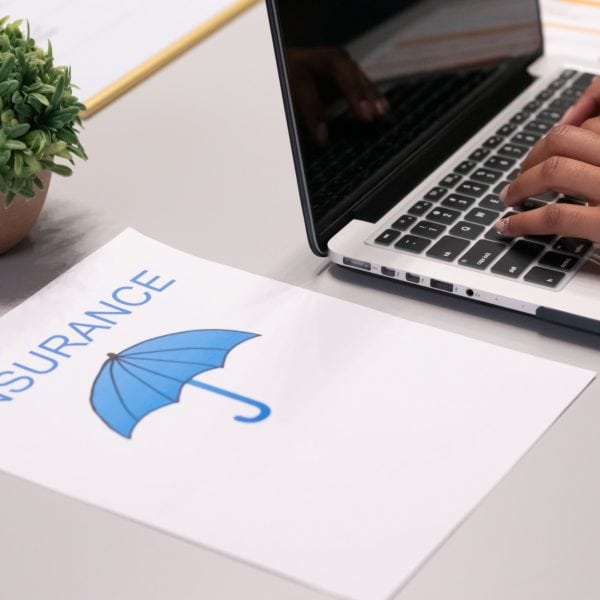 A person working on financial and insurance tasks, typing on a laptop with an umbrella on it.