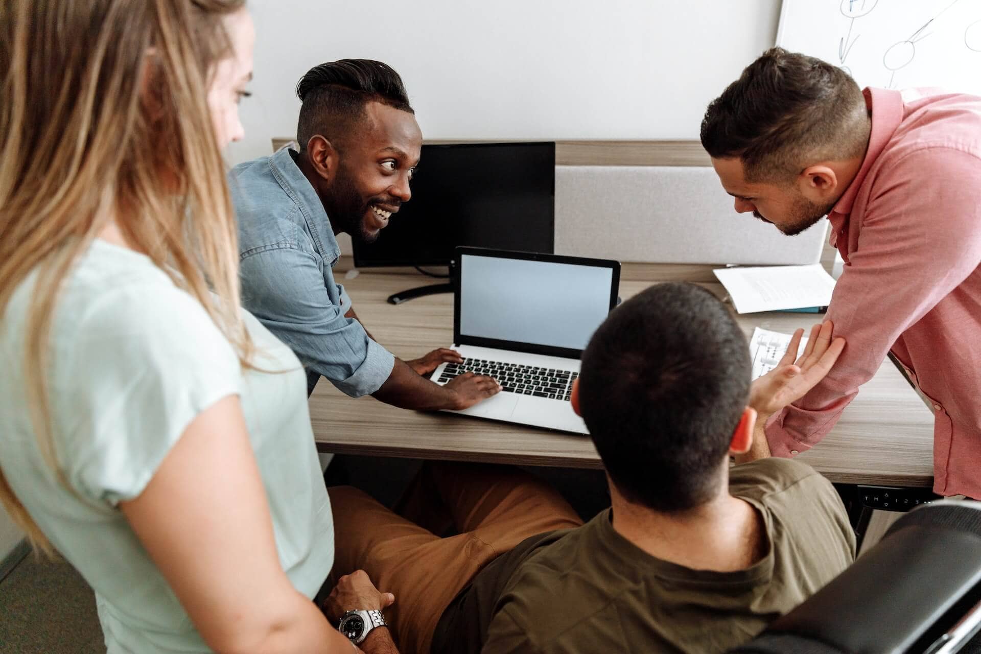 A group of people looking at a laptop in an office.