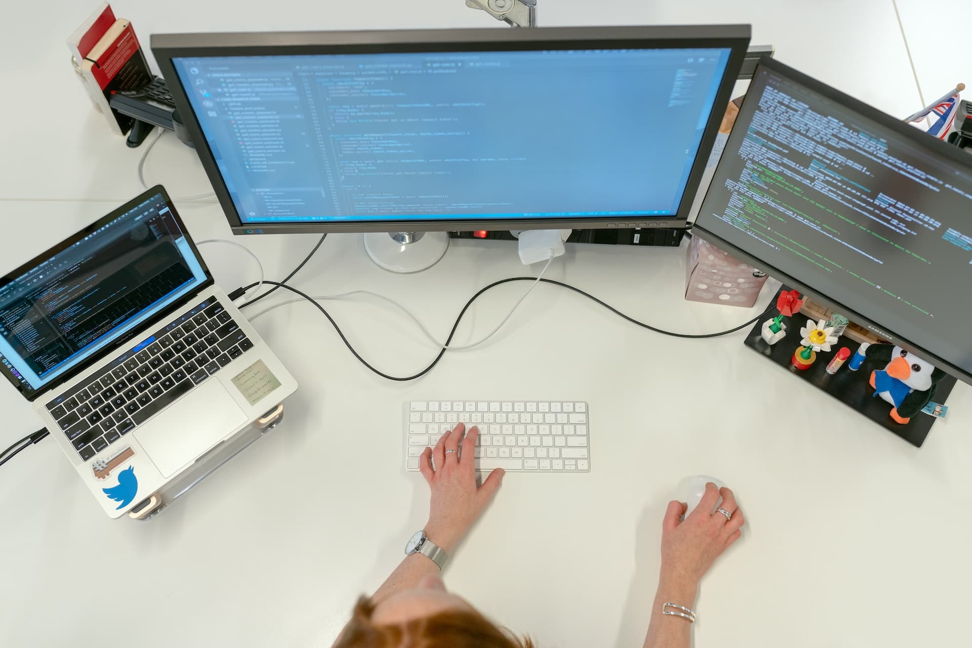 A SaaS professional overseeing tasks on two monitors and a keyboard while seated at a desk.