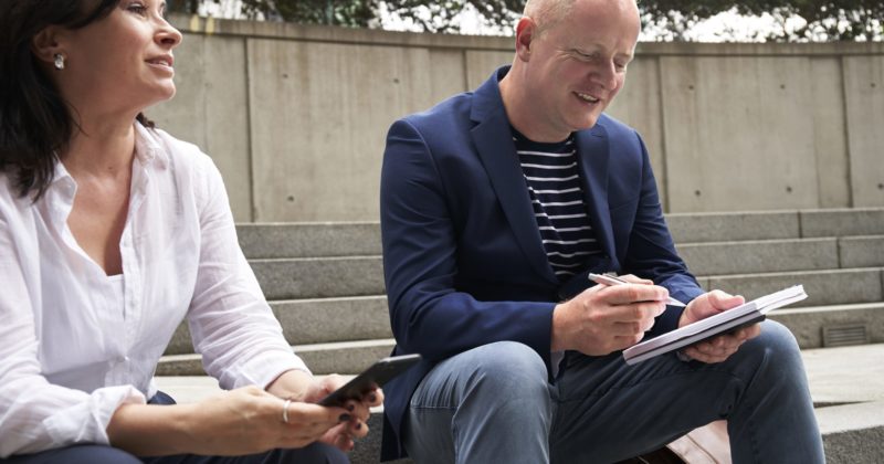 A woman and a man casually chat on steps.