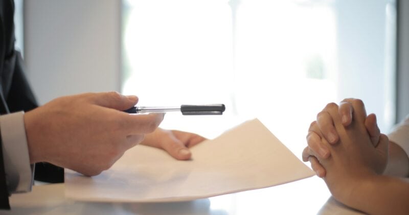 A consultant is providing a professional document to a woman.