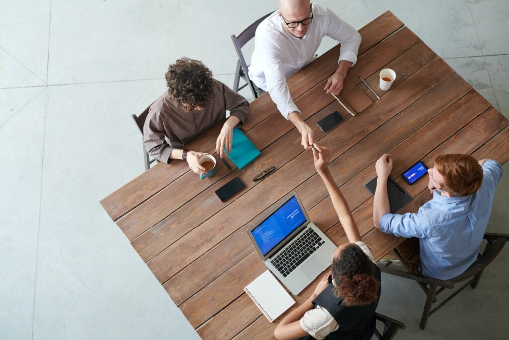 A group of people at a table exchanging high fives during a website redesign meeting in Chicago.