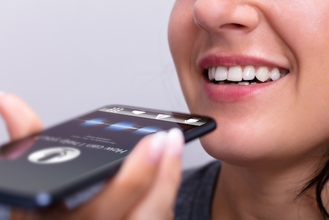 A woman is using a smart phone for voice search optimization.