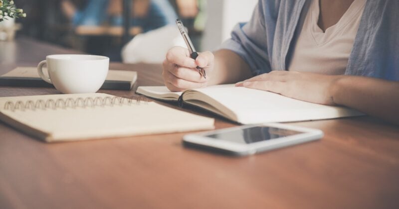 A woman writing an introduction for a blog post with a cup of coffee.