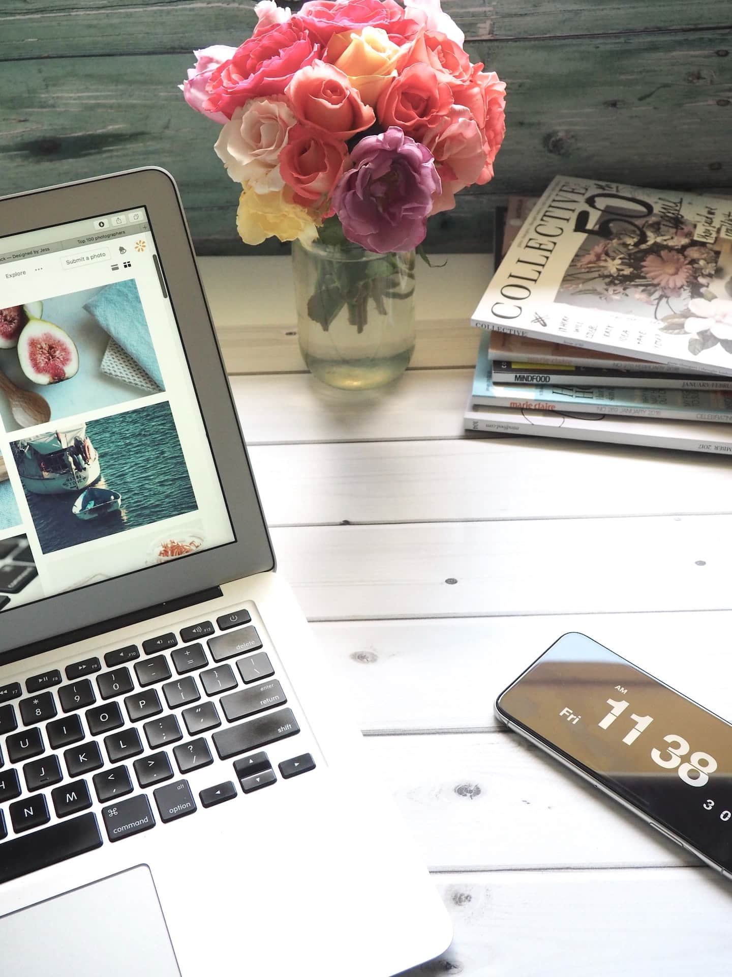 A table adorned with a laptop, cell phone, and flowers.