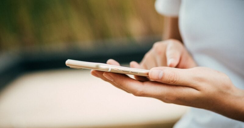 A woman's hand holding a cell phone that may reveal common mistakes on contact pages.