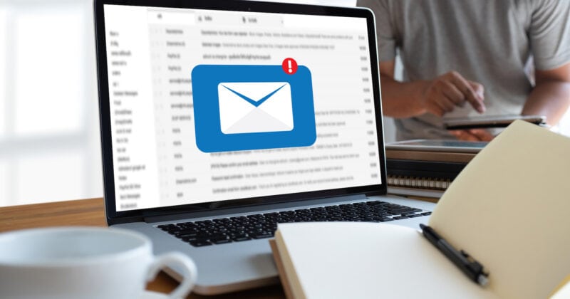 A man is sitting at a desk with a laptop, focusing on email.