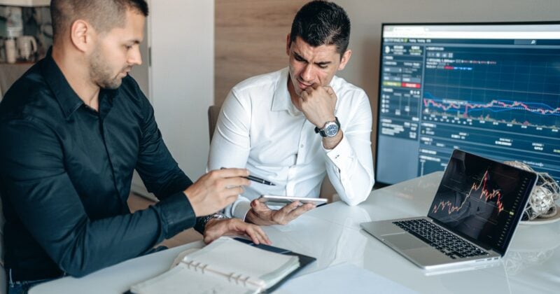 Two men analyzing the 20 best financial services websites on a computer screen at a desk.