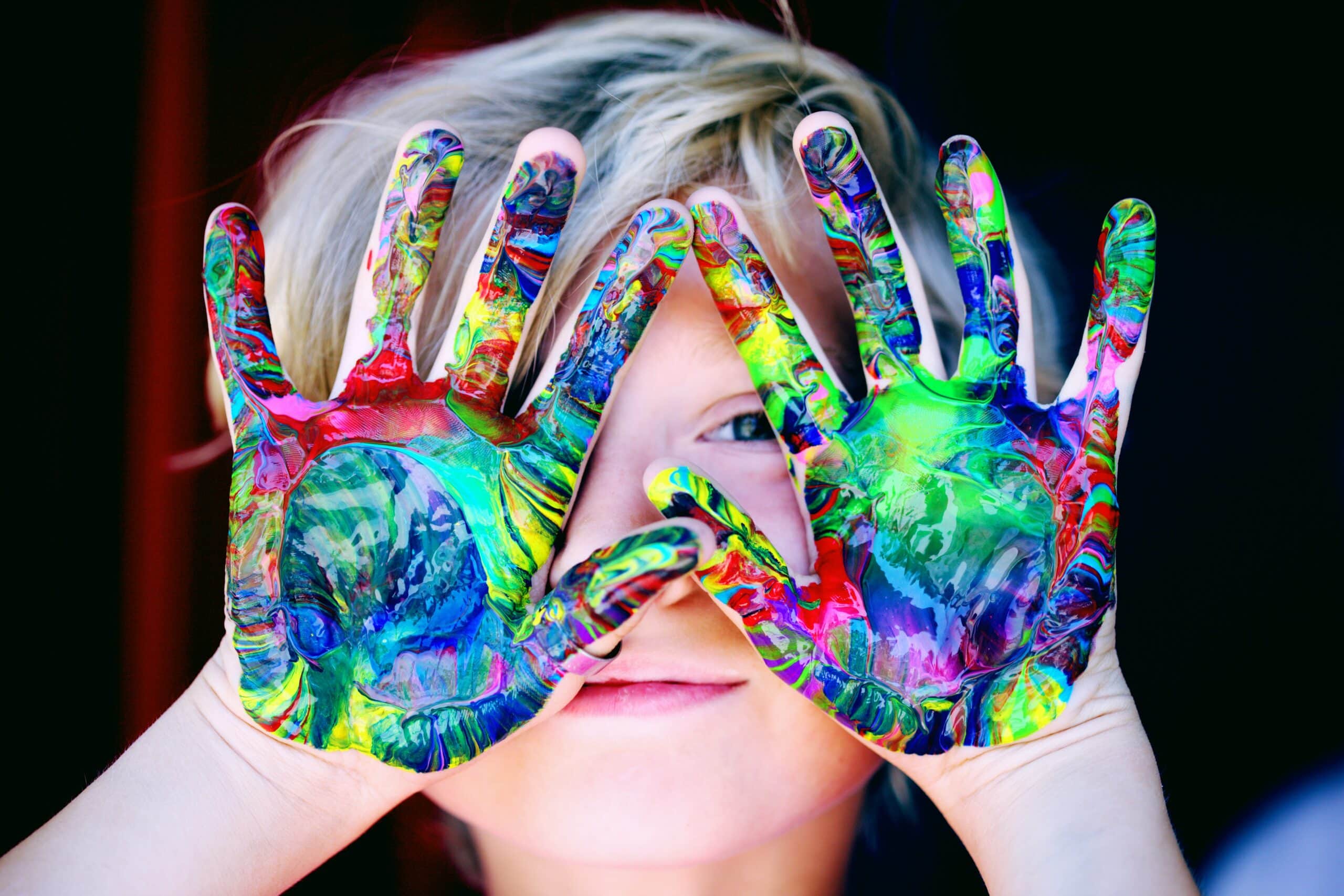 A child with colorful painted hands symbolizing the impact of color psychology on websites.