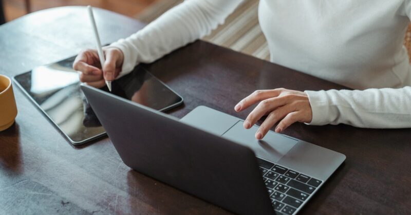 A woman utilizing a laptop to implement 5 Secrets to Ramp Up Local SEO strategies, accompanied by a cup of coffee on the table.