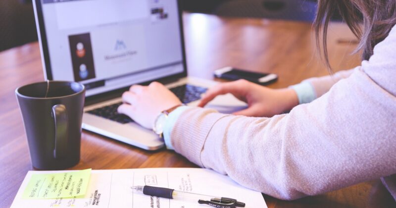 A woman creating visually appealing content on a wooden table with her laptop.