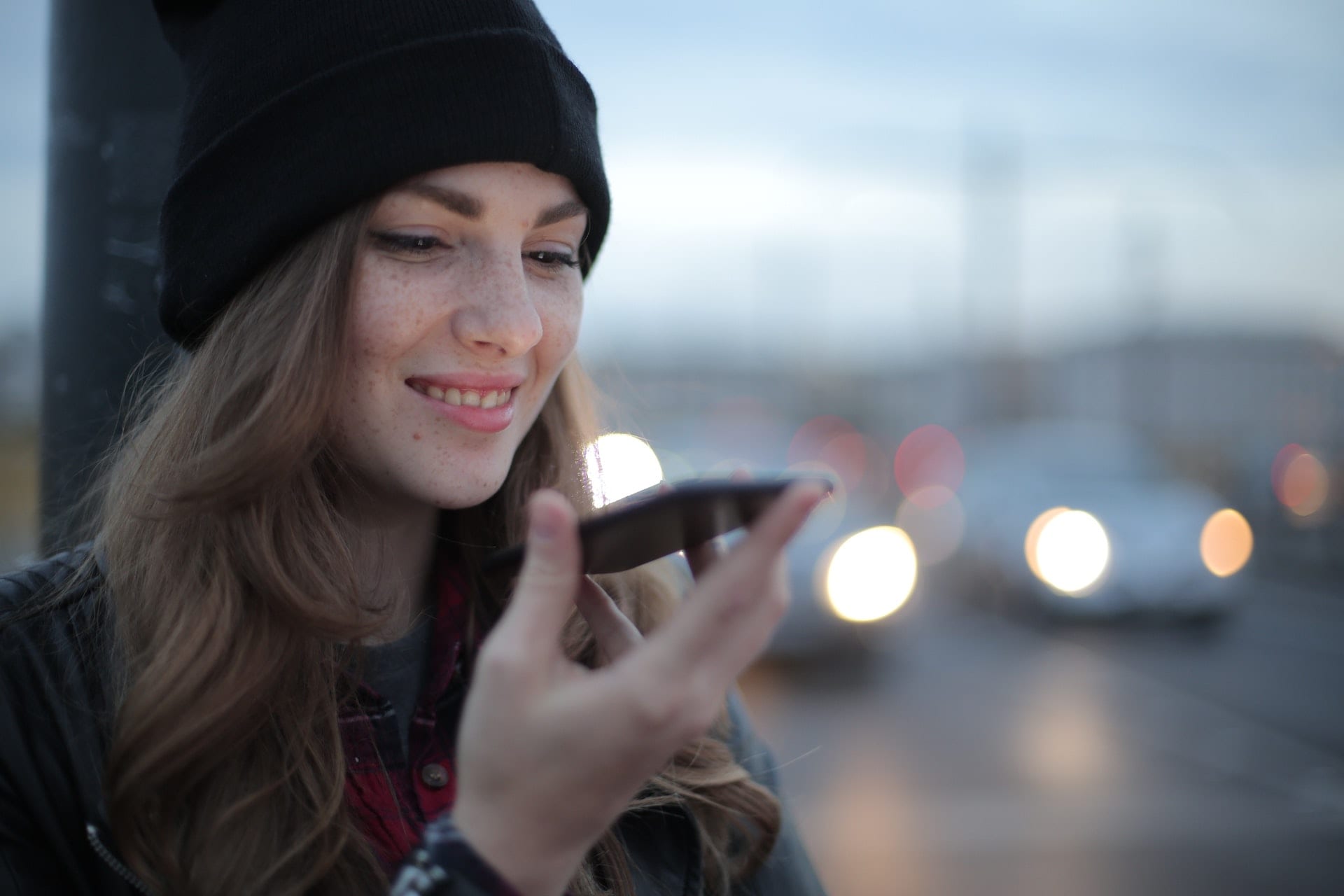 A young woman searching on her cell phone for 5 Secrets to improve Local SEO in the street.