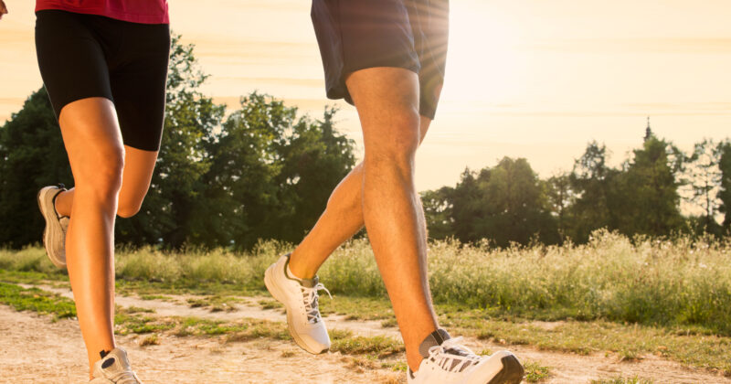 Two people exercising on a dirt road at sunset.