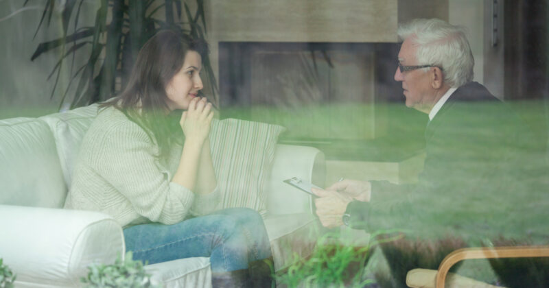 A man and woman engaging in conversation on a couch.