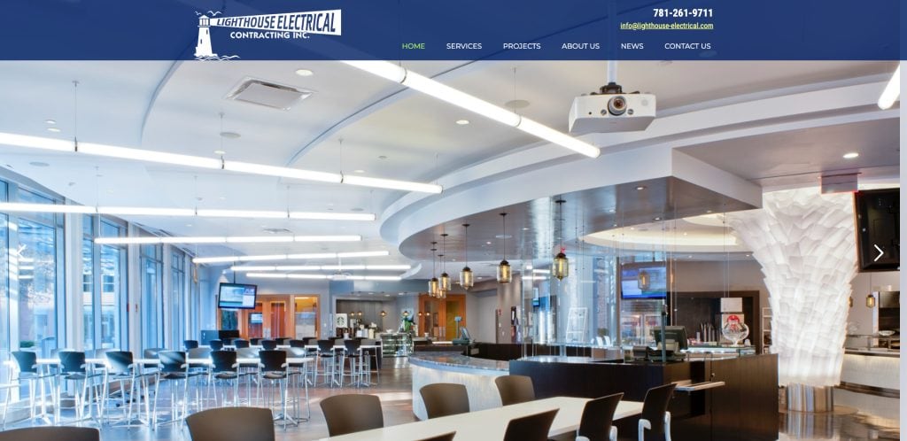 Modern, spacious office cafeteria with large windows, curved ceiling, sleek lighting, and rows of tables and chairs; a showcase of exceptional electrician website design for Lighthouse Electrical Contracting Inc.