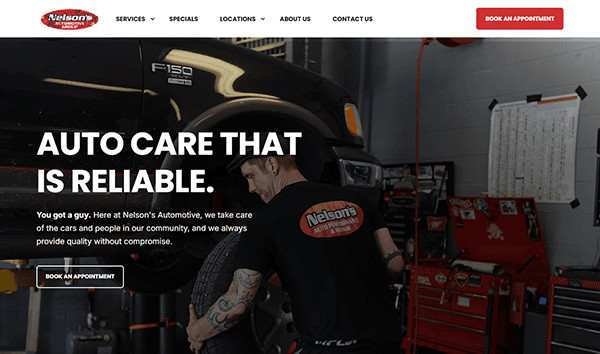 A mechanic works on the front wheel of a black pickup truck inside an auto repair shop. The text promotes reliable, best auto repair at Nelson’s Automotive—your trusted choice among leading auto repair websites.