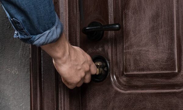 A man is opening a brown door that leads to a post-sale event.