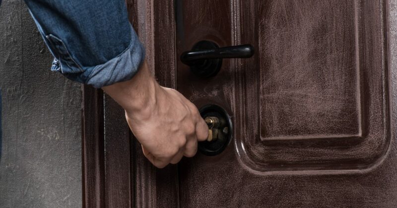 A man is opening a brown door that leads to a post-sale event.