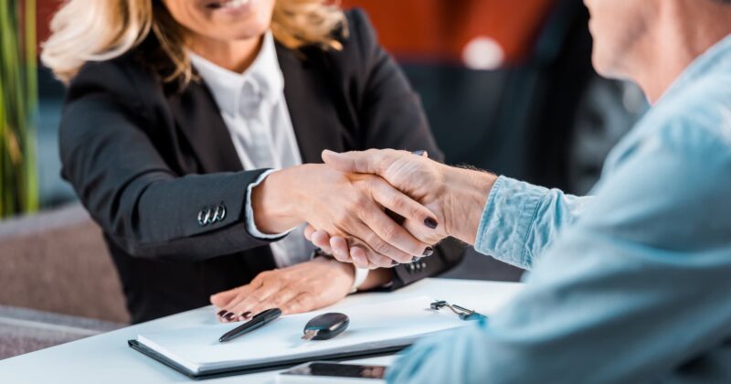 A buyer and seller shaking hands at a table.