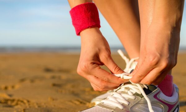 A woman tying her shoes on the beach, captured by a talented photographer.