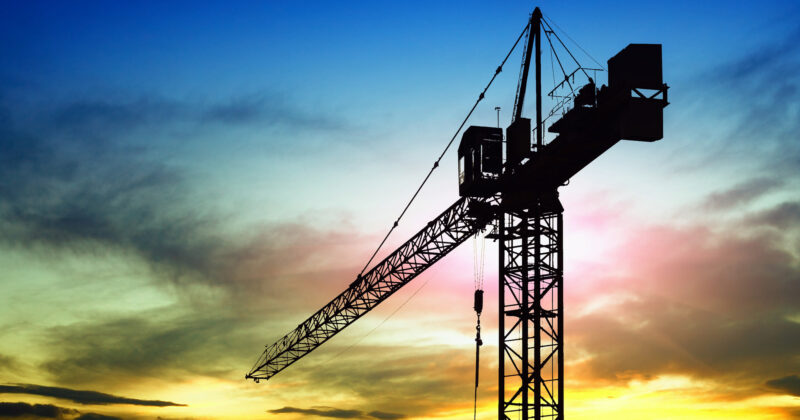A silhouette of a construction crane at sunset, perfect for commercial construction websites.