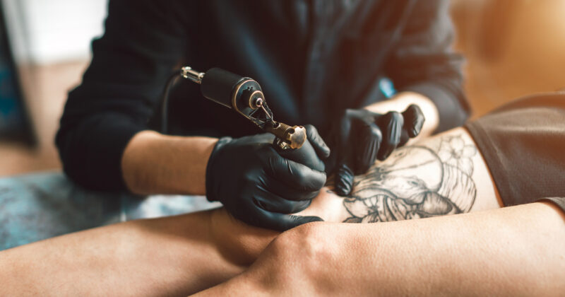 Tattoo artist creating a design on a client's leg at the best tattoo shop.